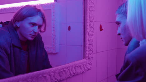 Couple-Looking-in-Mirror-and-Talking-in-Room-with-Neon-Purple-Light