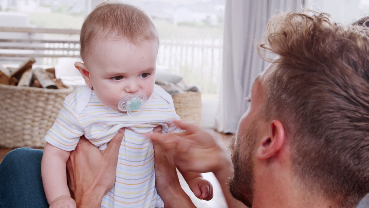 Over shoulder view of dad giving young toddler pacifier