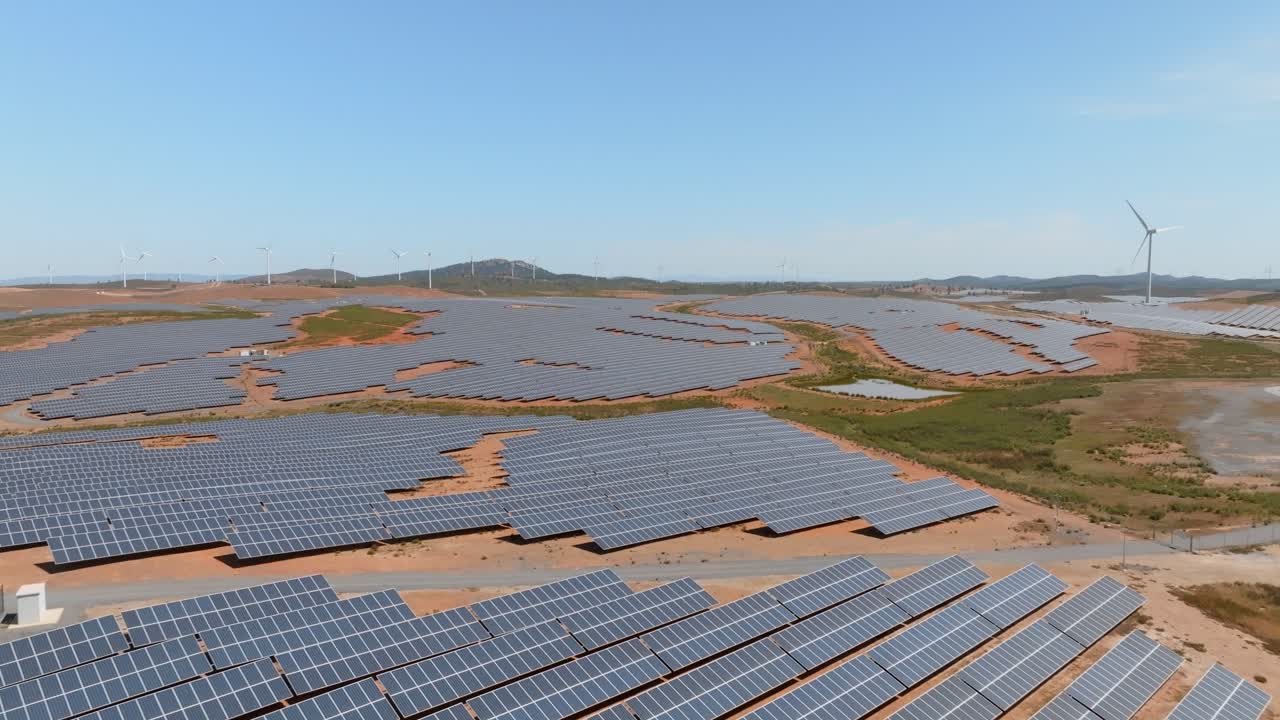 Drone dolly above large solar farm field built on hilly desert landscape
