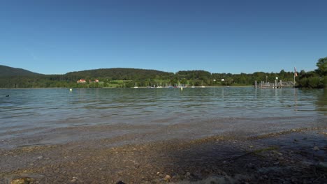 Little-waves-of-the-popular-bavarian-tourism-hotspot-Tegernsee,-a-beautiful-view-from-low-perspective-over-the-large-lake-in-southern-bavaria