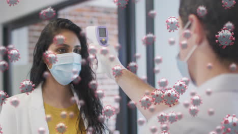 animation of covid 19 cells floating over man measuring temperature of his female colleague in face