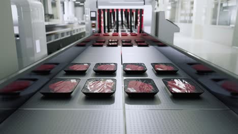 packaged raw meat trays on a conveyor belt in a factory