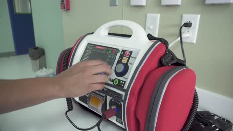 médico masculino demostrando una máquina de desfibrilación en el hospital