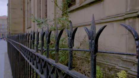 black wrought iron fence against a sandstone cathedral wall