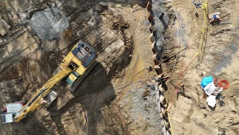 a construction site with heavy machinery and workers operating an excavator, aerial view