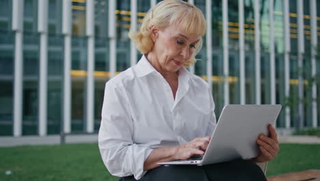 ejecutivo senior trabajando en línea en una computadora inalámbrica al aire libre.