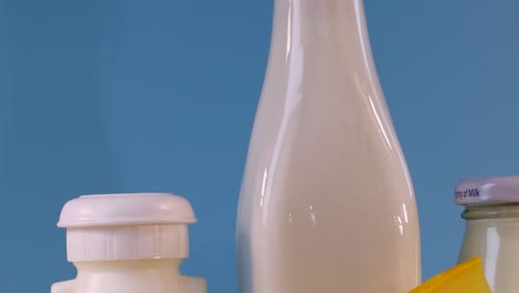 close-up of various dairy bottles and cheese against a blue backdrop.