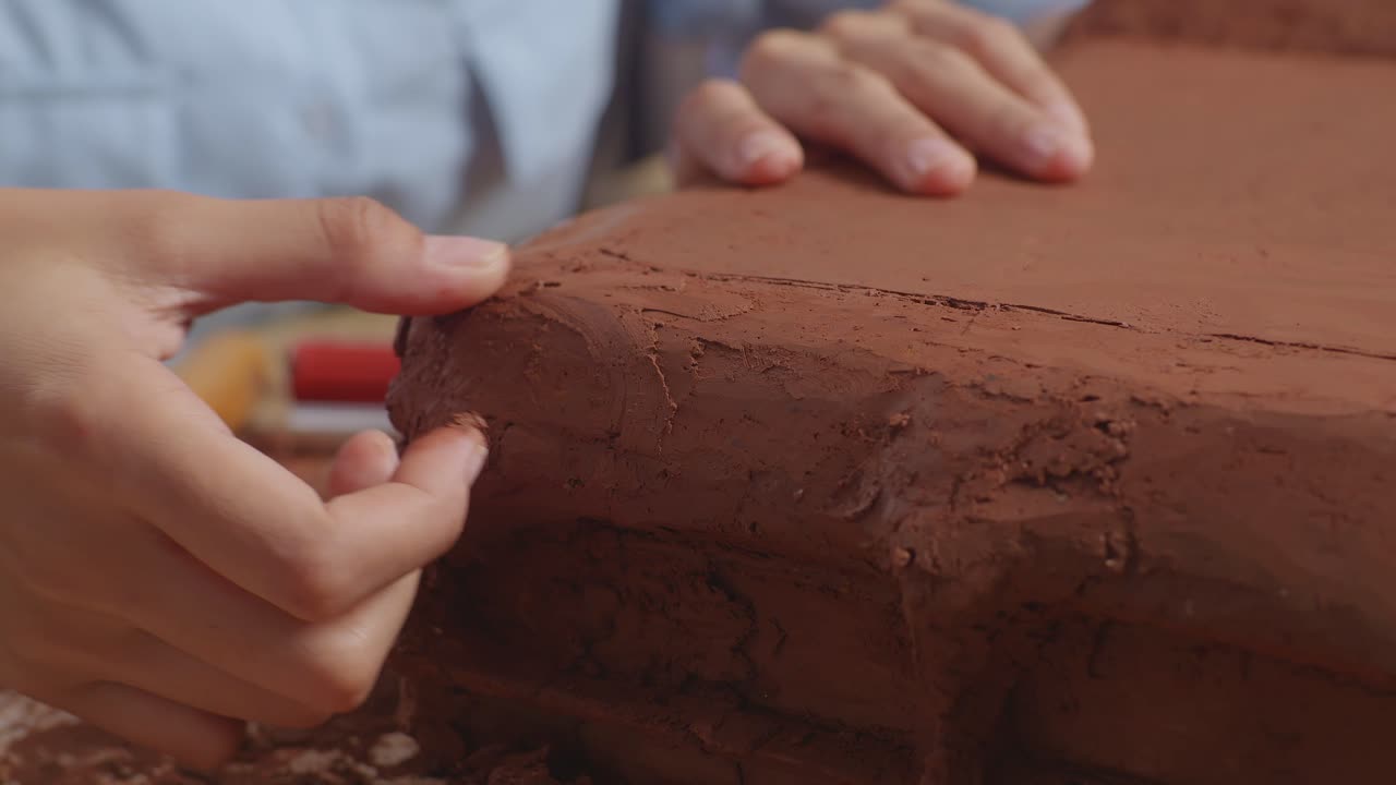 cerca de las manos de la mujer diseñador de automóviles suavizar la superficie y crear detalles en la escultura de arcilla de coche en el estudio