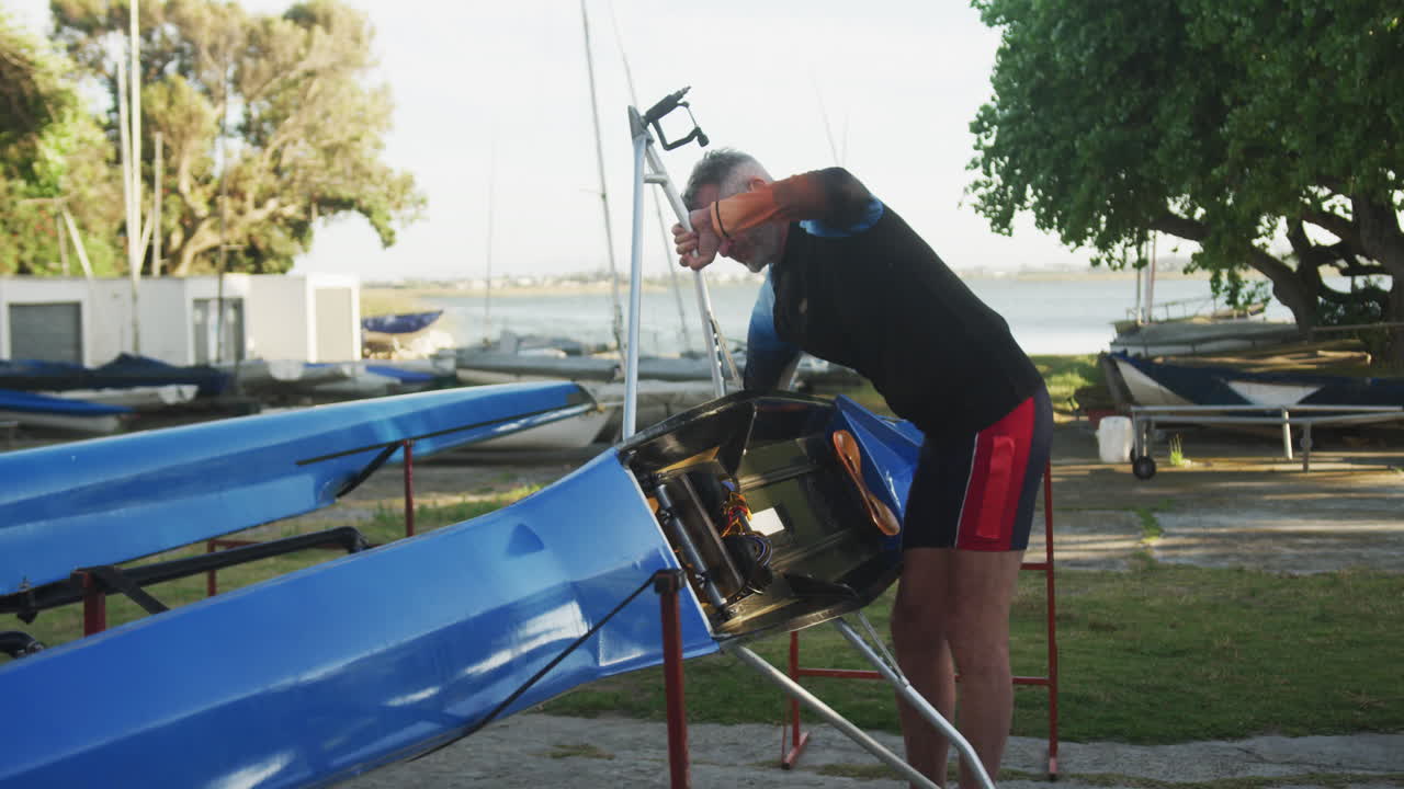 Senior caucasian man preparing rowing boat for the water