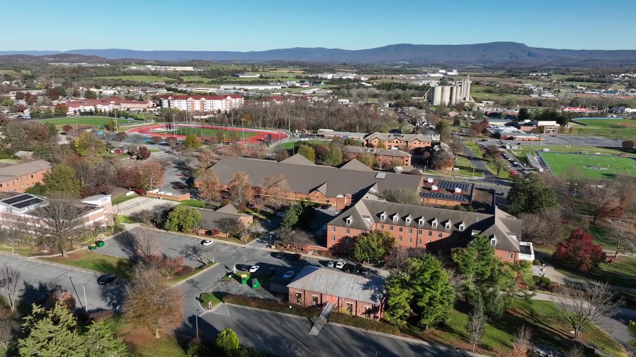 Naderende luchtopname van de historische Eastern Mennonite University in Harrisonburg op een zonnige dag. Herfstseizoen met gekleurde bomen in Virginia. Breedbeeld.