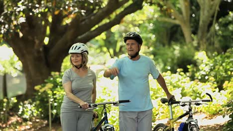 Senior-couple-walking-and-pushing-bikes