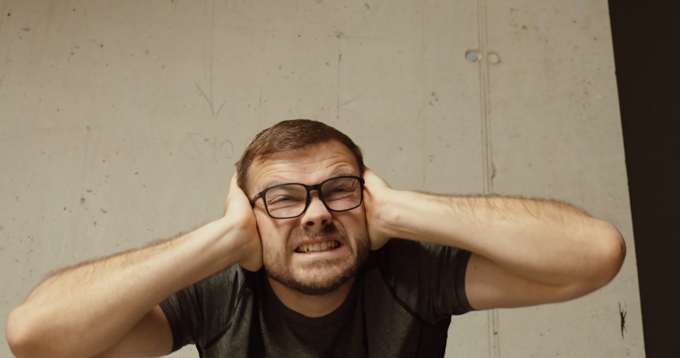 Close-up of a man covering his ears in fear during a loud explosion. Concept of war danger, rocket attack, shock, survival instinct, and civilian reaction to conflict.