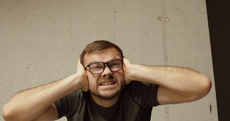 Close-up of a man covering his ears in fear during a loud explosion. Concept of war danger, rocket attack, shock, survival instinct, and civilian reaction to conflict.