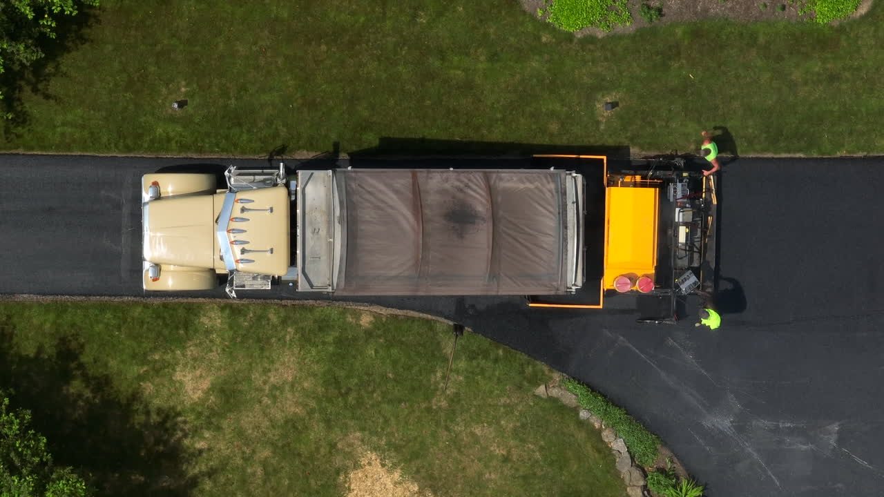 Top down aerial rising shot of truck paving driveway