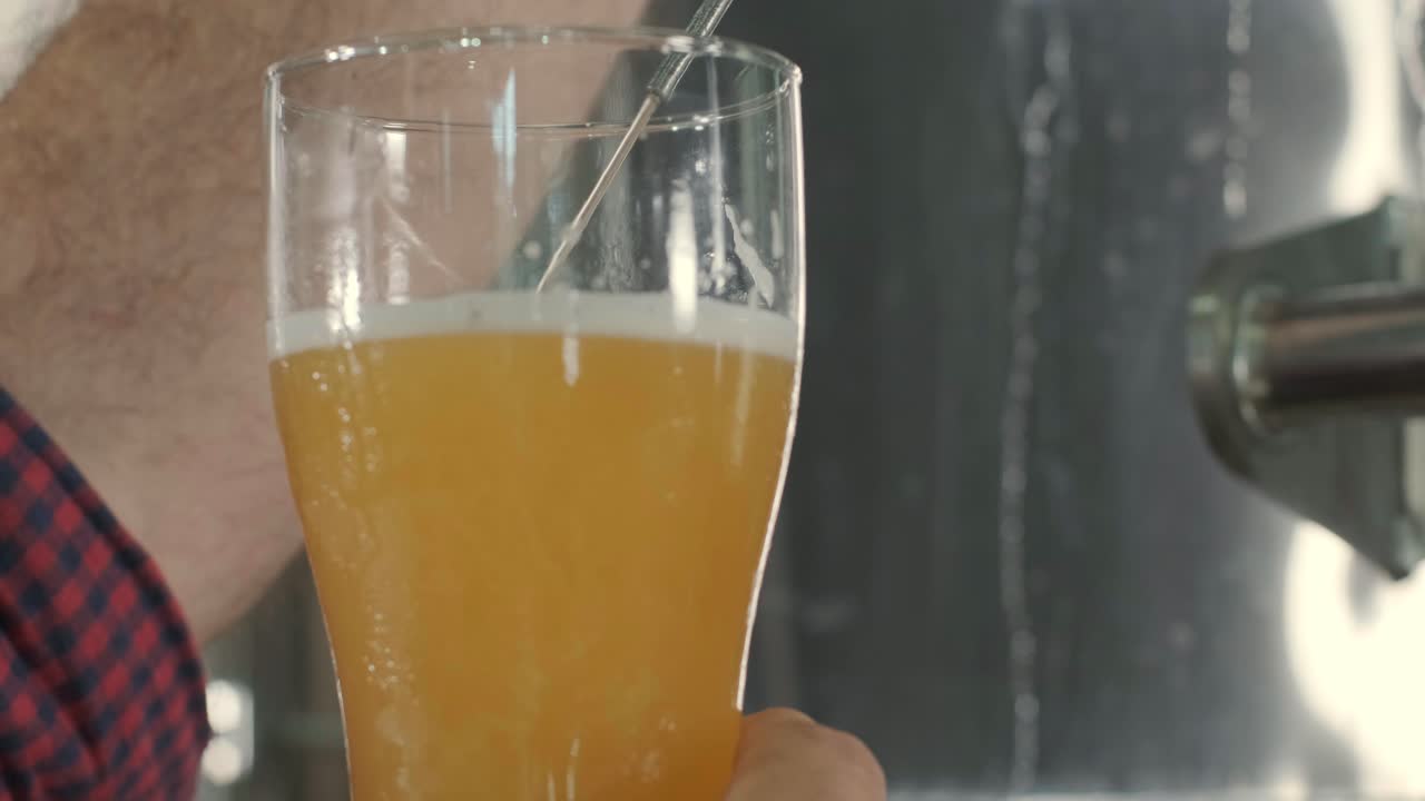 un joven cervecero con un delantal de cuero está probando cerveza en una cervecería moderna