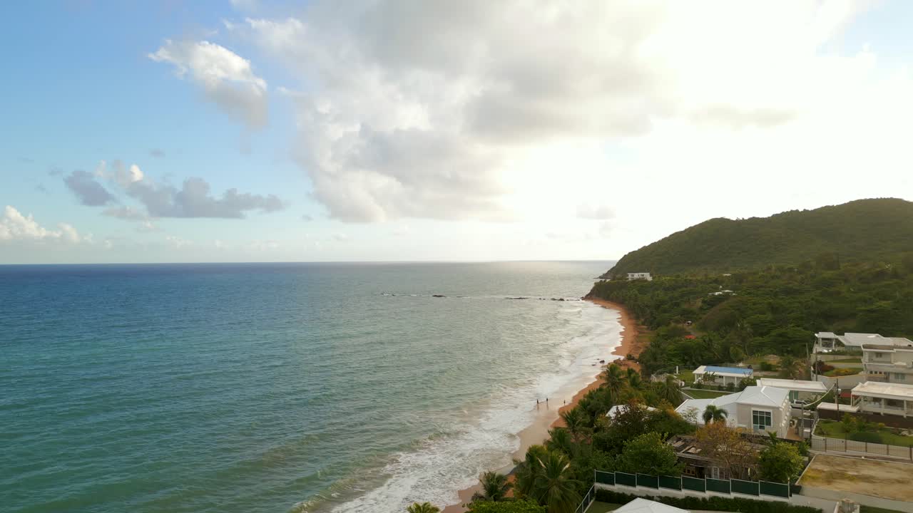 Tomada cinematográfica de drone de uma costa verdejante e exuberante e uma baía tropical calma em Porto Rico. Vista de ângulo elevado da paisagem da ilha encontrando o Oceano Atlântico durante um dia claro