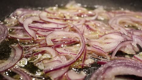 freír las cebollas rojas frescas con aceite caliente en una sartén de acero - imágenes de primer plano