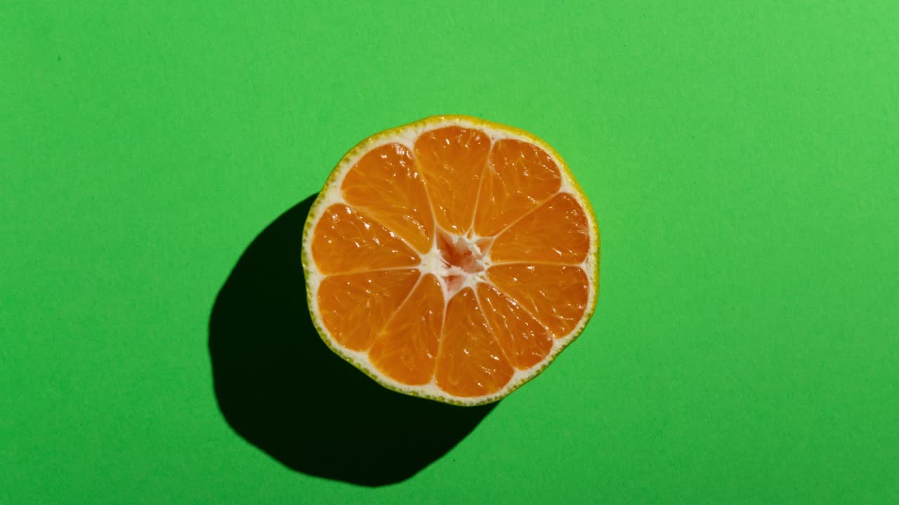 Mezzi mandarini freschi con ombra marcata su sfondo verde. Animazione stop motion di cibo