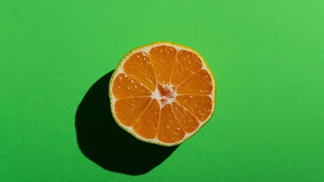 mitades de mandarina frescas con una fuerte sombra en un fondo verde. animación de alimentos en movimiento de parada