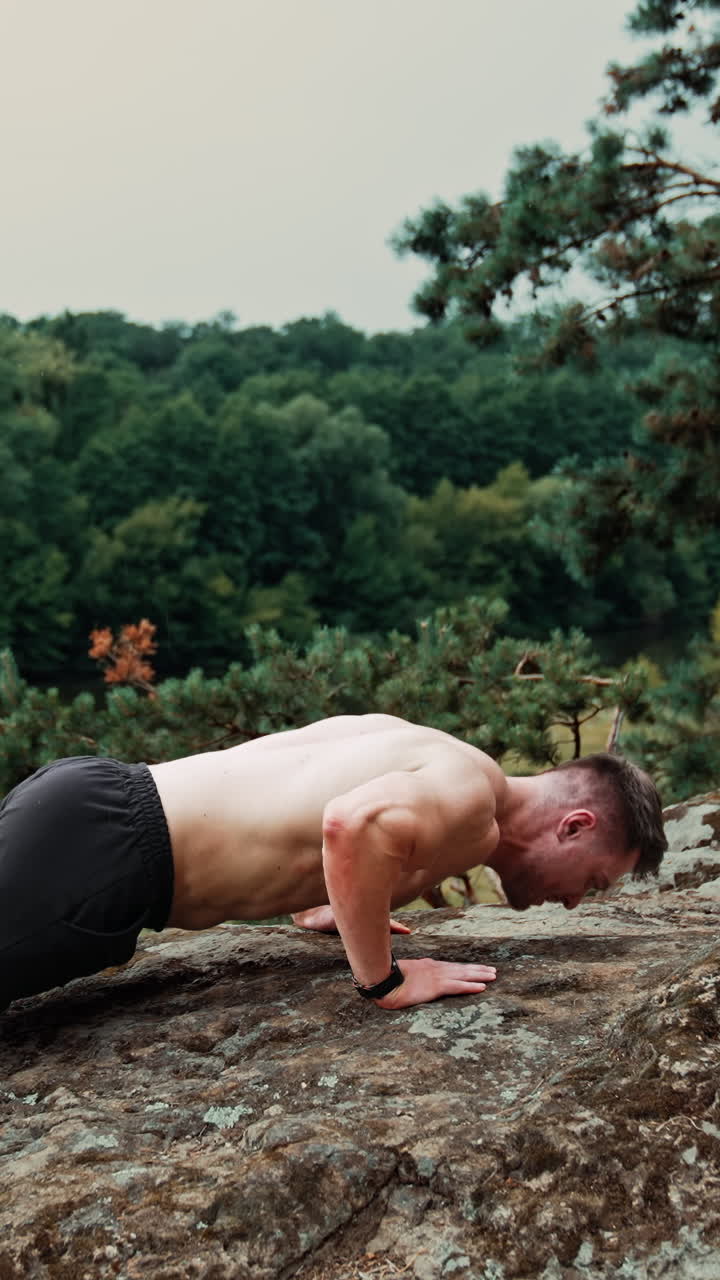 Sportsman doing pushups on the big rock. Exercising, work out and healthy lifestyle in the nature. Vertical video