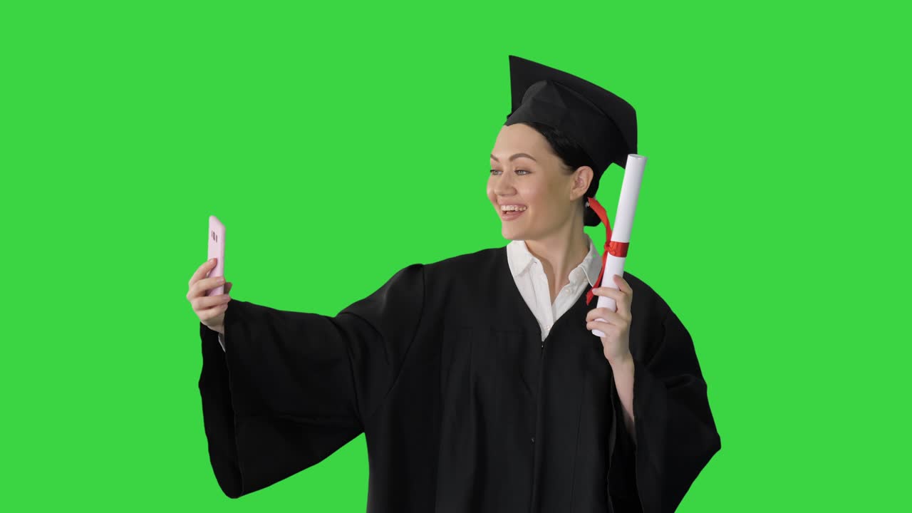 Laureata felice che tiene in mano il diploma e si fa un selfie con il suo telefono su Schermo Verde, Chroma Key