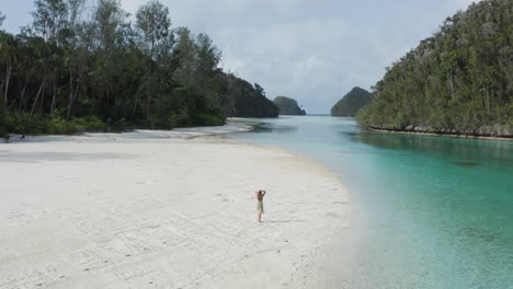 model walking on white sand beach in tropical paradise with turquoise water