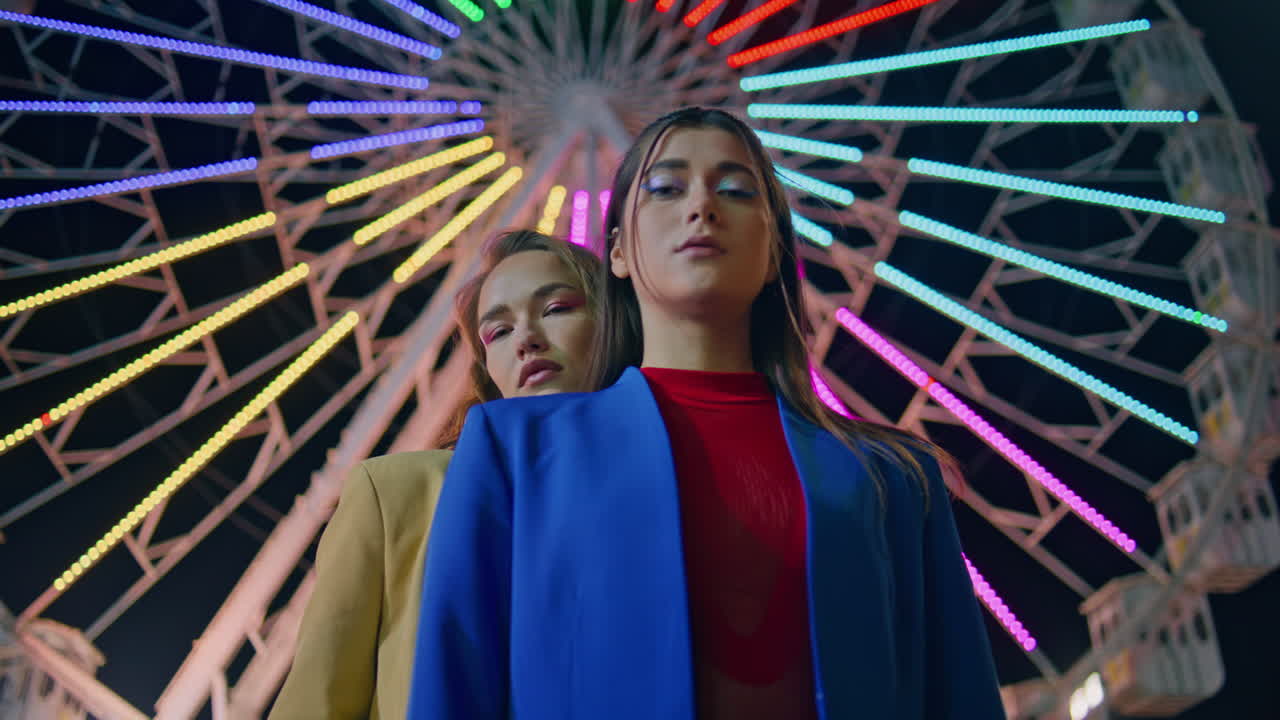 modelos posando en el parque de atracciones de noche en primer plano. chicas hermosas descansando en ferris