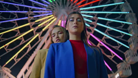 modelos posando en el parque de atracciones de noche en primer plano. chicas hermosas descansando en ferris