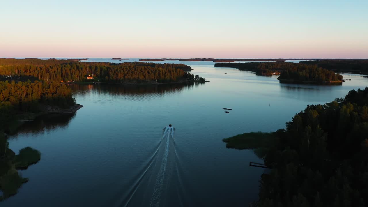 Vista aerea che segue un'imbarcazione che naviga al centro delle isole, colori vivaci, tramonto estivo nell'arcipelago svedese di Stoccolma, nel Golfo di Botnia, in Svezia - dolly, ripresa con drone