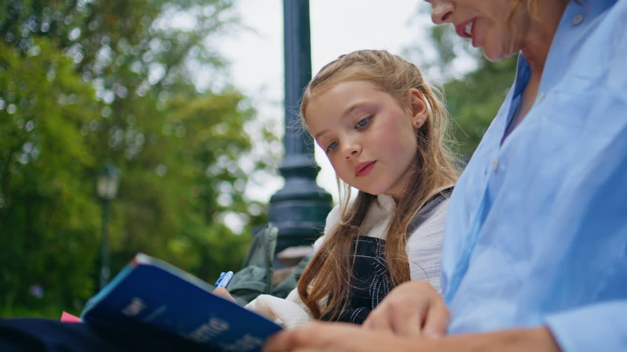 Thoughtful child doing homework at fresh air with parent closeup. Pensive kid