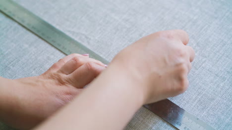 woman-makes-cut-dense-fabric-with-chalk-piece