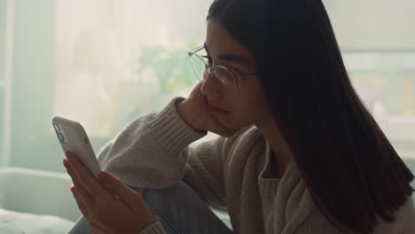 caucasian teenage girl browsing phone while sitting on bed