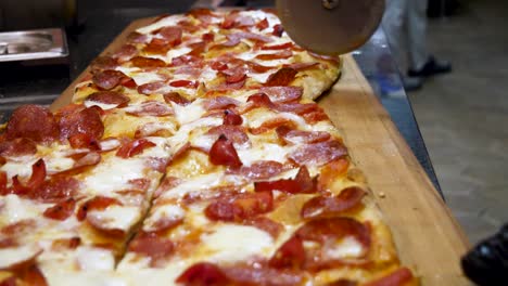 cutting a large pepperoni pizza