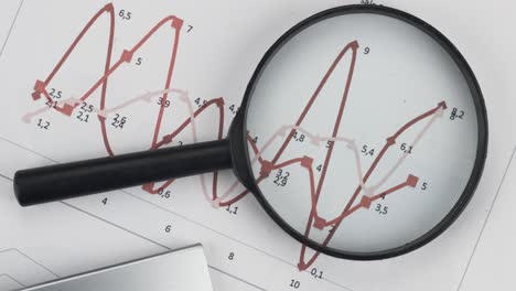 rotation of a magnifying glass and a calculator lying on a red chart