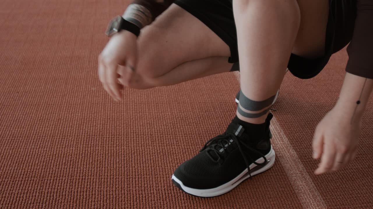 Close-up of a person tying running shoes on a track