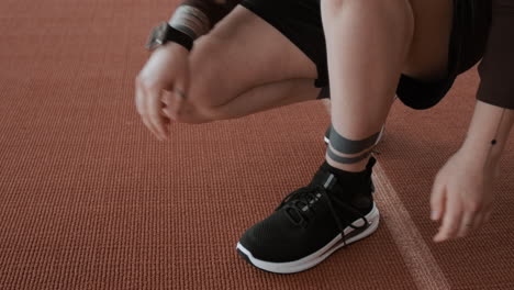 close-up of a person tying running shoes on a track