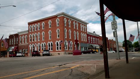 Antique-stoplight-in-downtown-Toledo,-Iowa-with-man-walking-up-to-the-stoplight