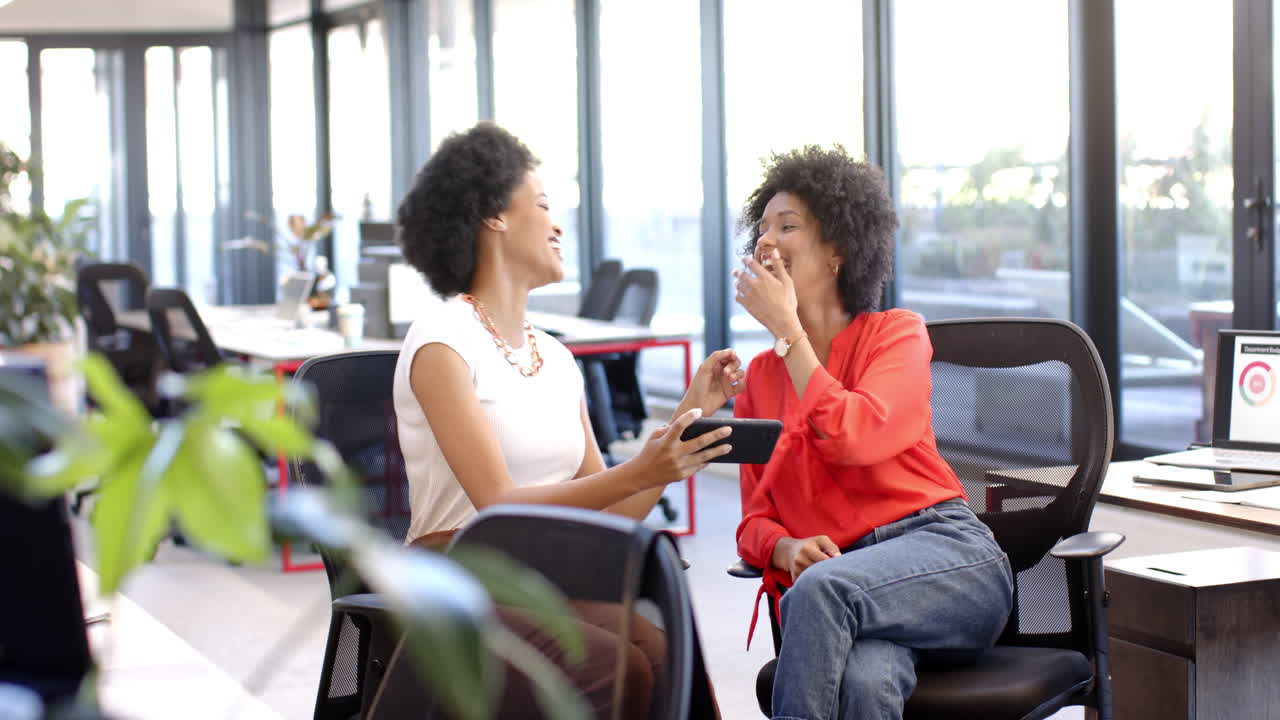 African American and biracial women colleagues laughing together in office