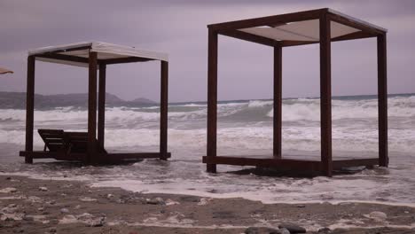 foamy waves crashing over shore with wooden sunshades gazebo