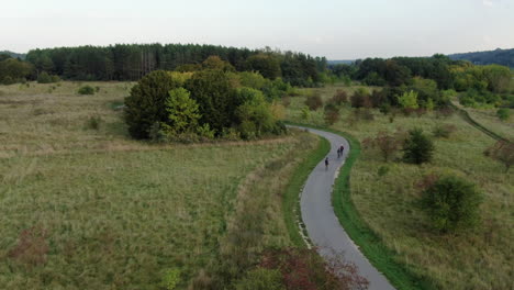 grupo de personas andan en bicicleta en la moderna carretera asfaltada, vista de seguimiento de drones aéreos