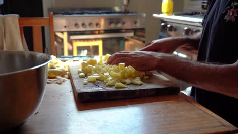 close up of a person slicing raw potatoes on a wooden chopping board