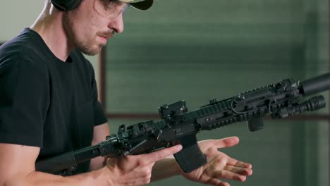 a man loads a magazine clip onto a rifle and fires a round at an indoor firing range