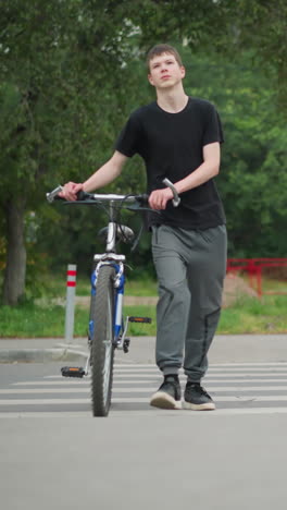 색 페인트로 표시된 보행자 교차로에서 두 친구가 자전거와 함께 나란히 걸어가고 있으며, 배경에는 지나가는 자동차, 초록색 나무, 밝은 빨간색 울타리가 있습니다.
