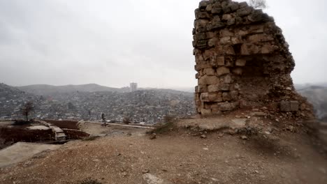 surviving wall inside ruins of urfa castle on background modern city snow and rain