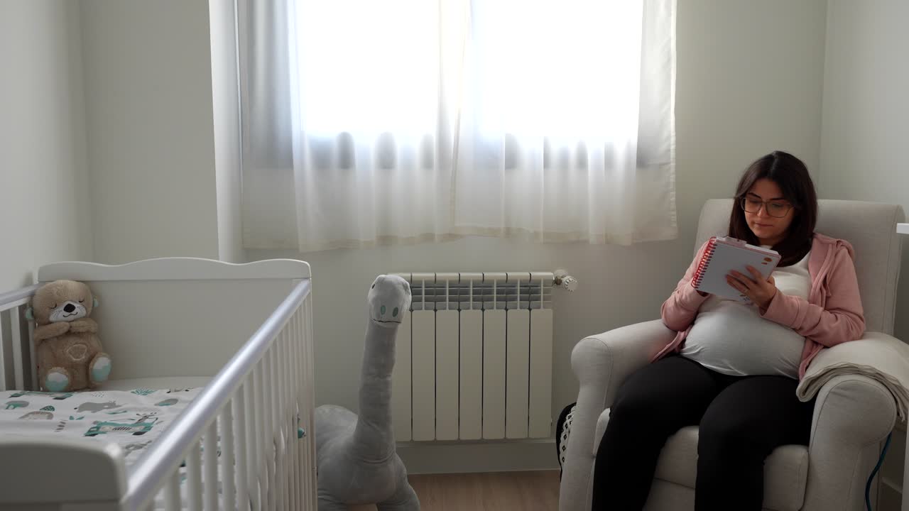 Pregnant woman writing notes on what is pending for the future baby