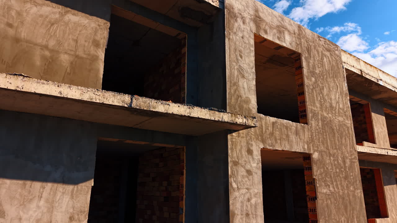 Edifício alto de tijolos com portas vazias. Subindo até o topo da casa com telhado de madeira. Céu azul com nuvens brancas ao fundo