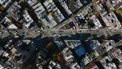 Aerial-birds-eye-overhead-top-down-panning-view-of-cars-driving-on-wide-street-surrounded-by-blocks-of-buildings.-Manhattan,-New-York-City,-USA