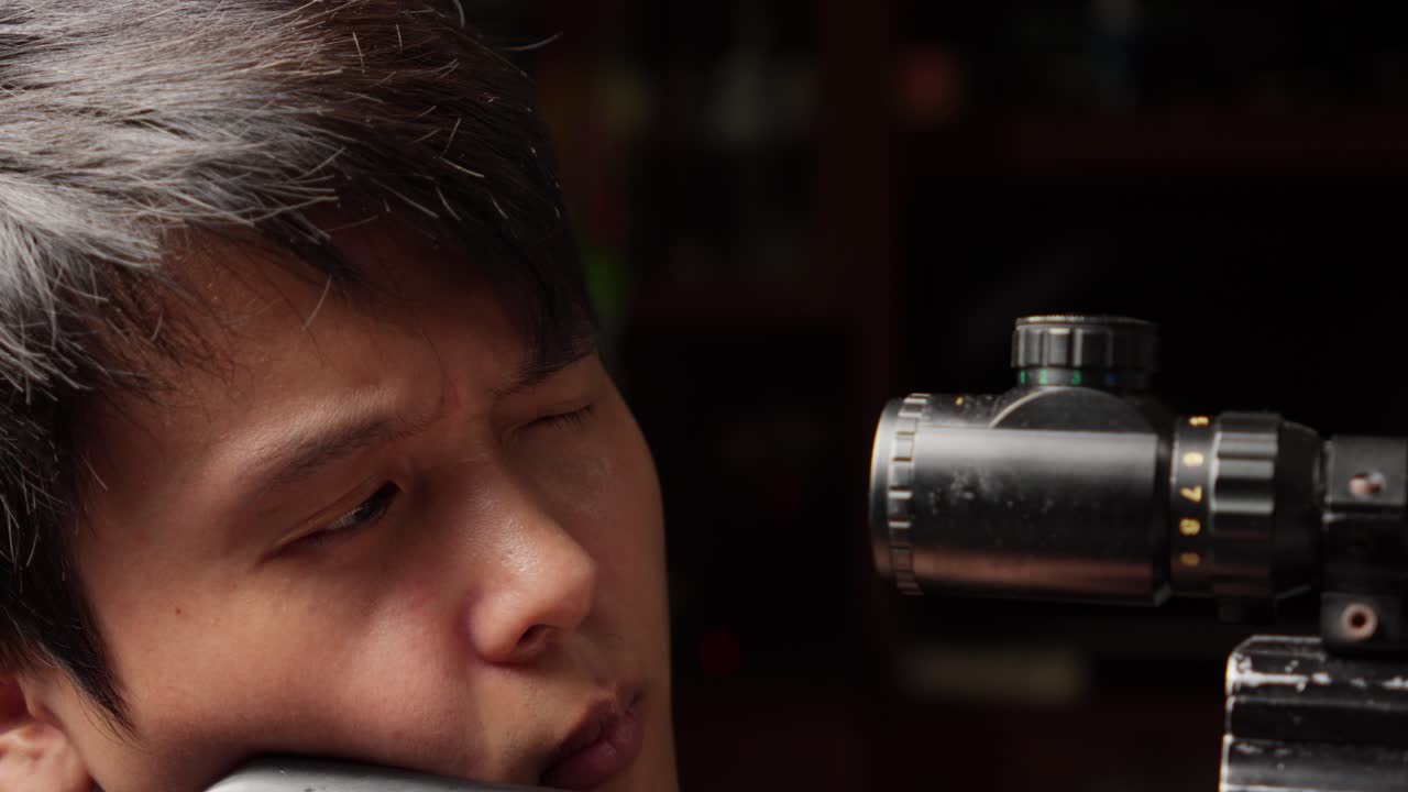 아시아의 저격수 남자가 보를 조정하고 느린 동작으로 총을 습니다.