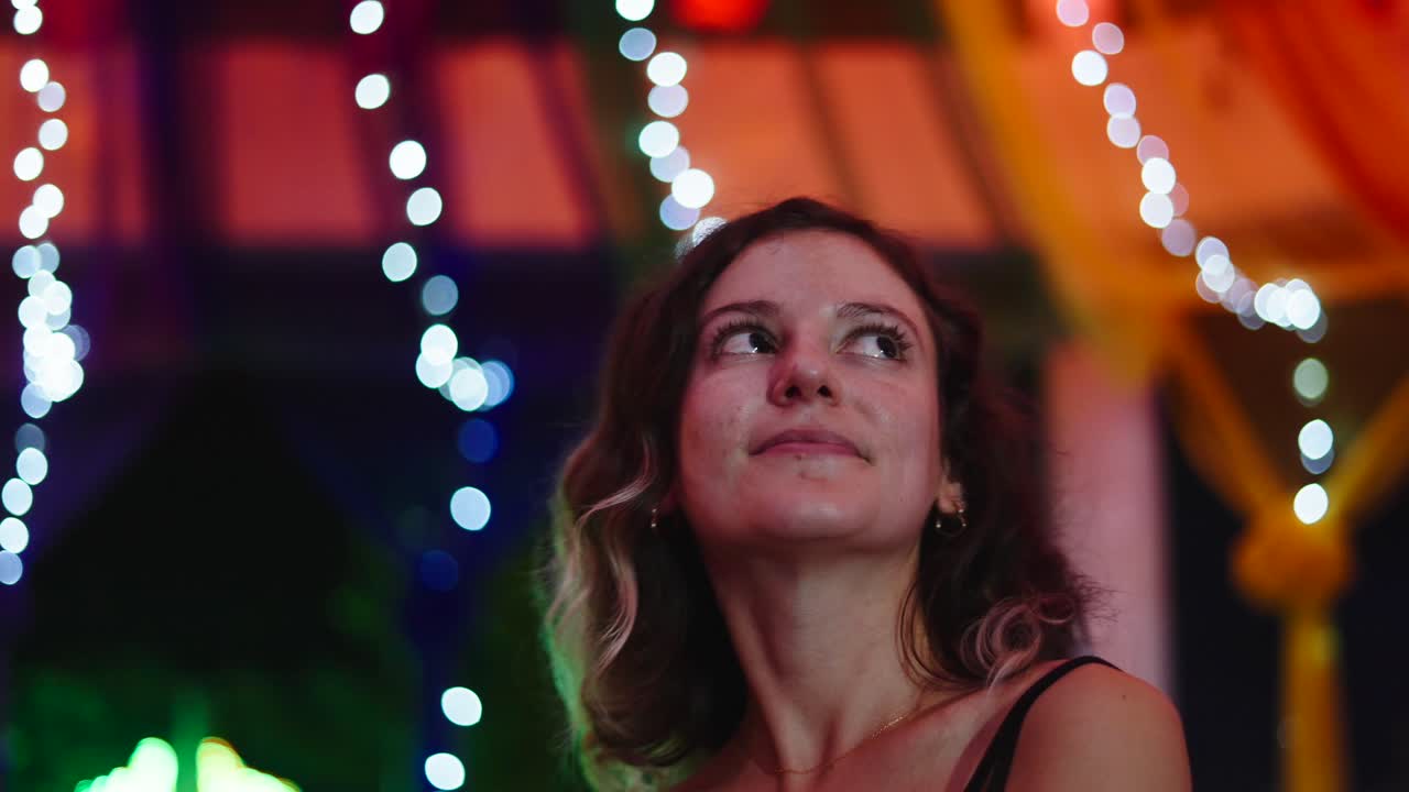 Woman looking up at colorful lights