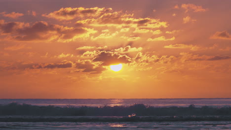 Atemberaubender-Wärmender-Orangefarbener-Strandsonnenuntergang-Mit-Dunklen-Wellen,-Die-Ins-Ufer-Rollen